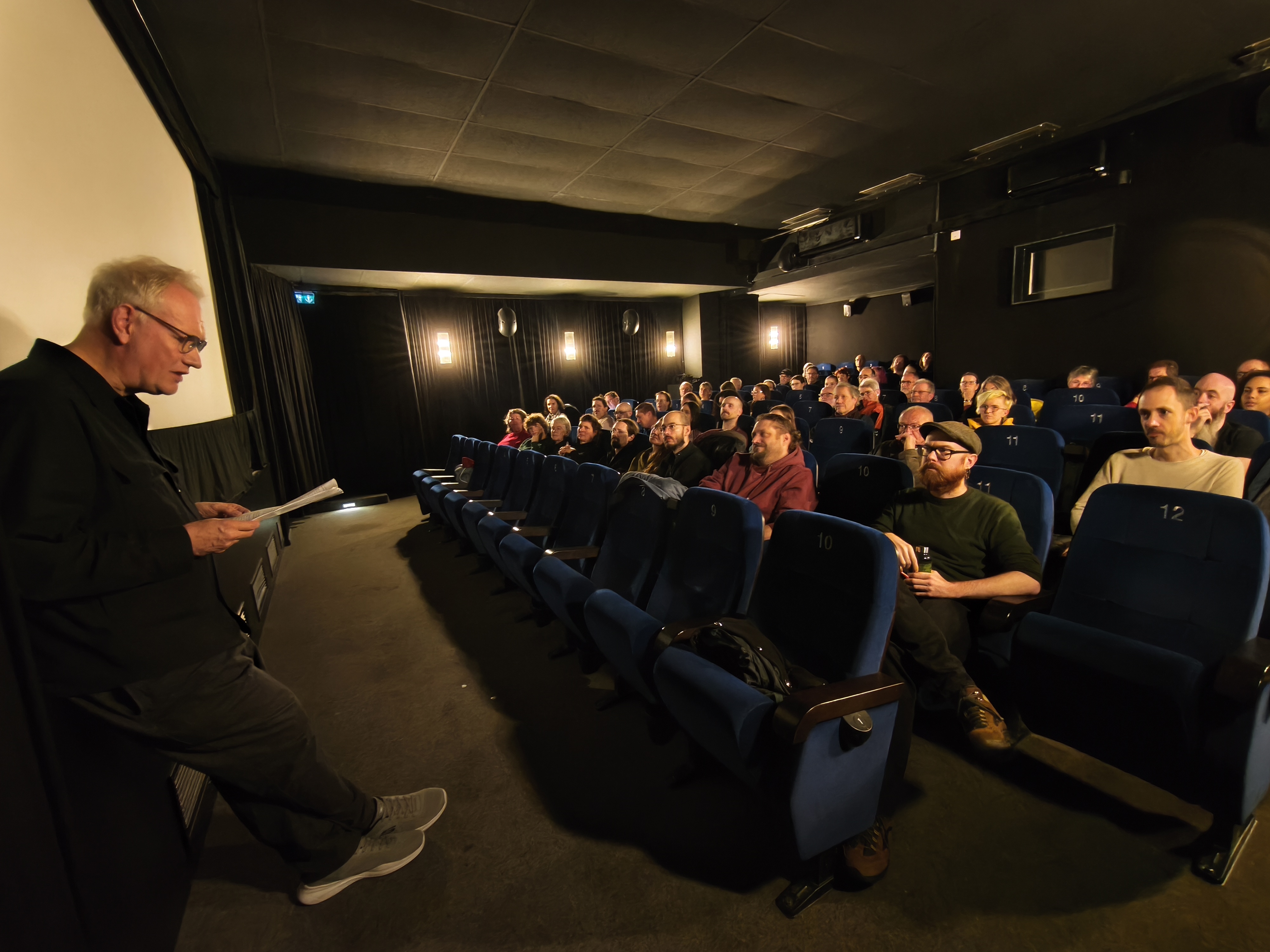 Publikum in einem Kinosaal mit beleuchteter Leinwand